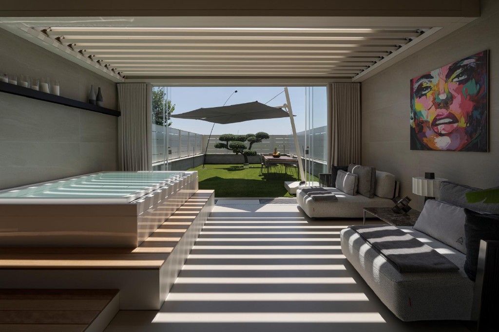 Area spa diurna: mini-piscina, lounge e giardino d’inverno oltre le vetrate.
