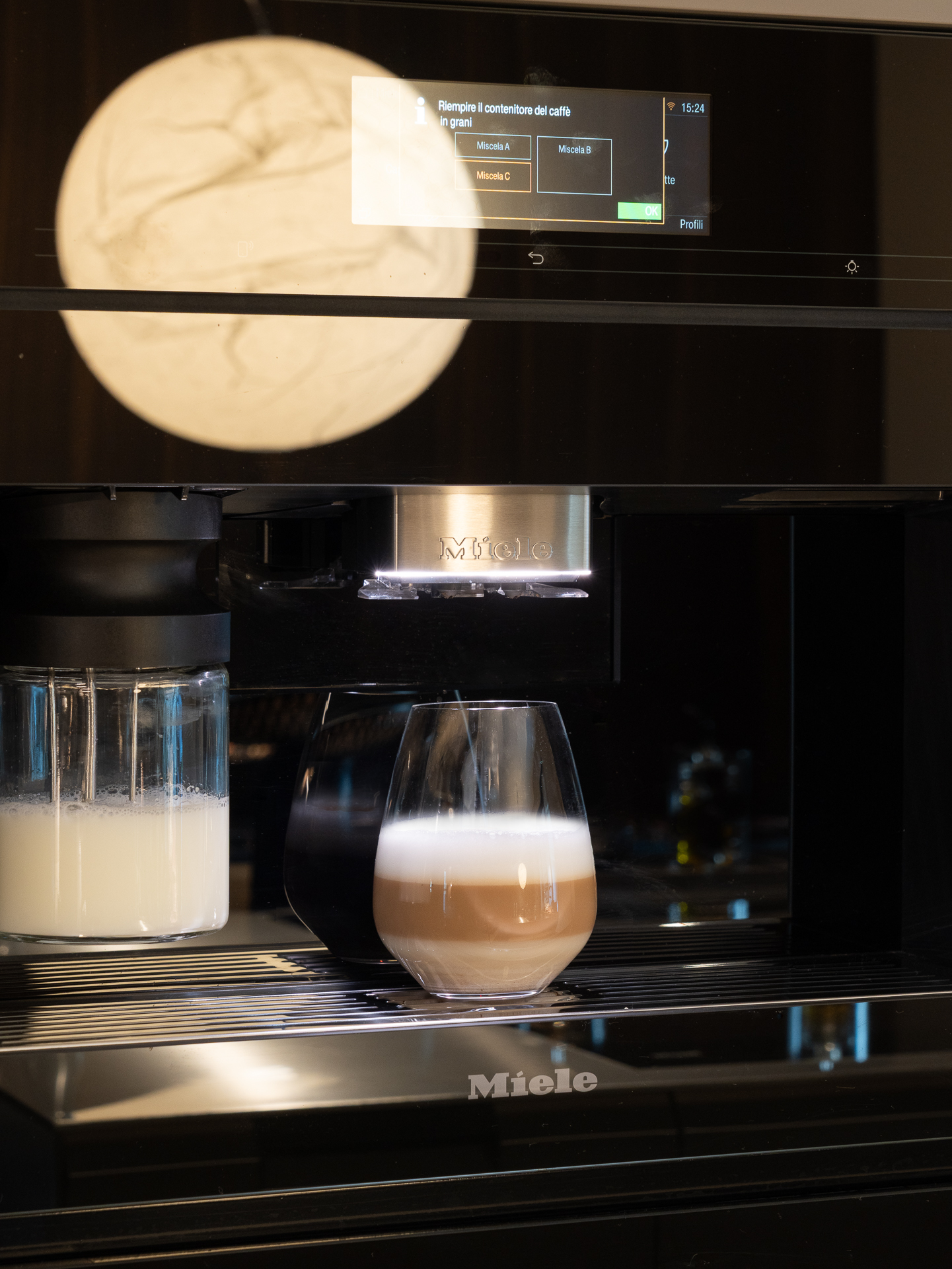 Macchina da caffè Miele a incasso: espresso e latte nella penombra della cucina.